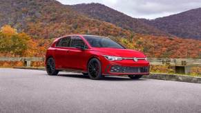 A red 2023 Volkswagen Golf GTI parks next to a perfect Boost Season landscape.