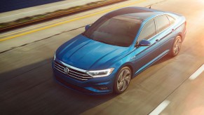 A blue 2023 Volkswagen Jetta driving down the street