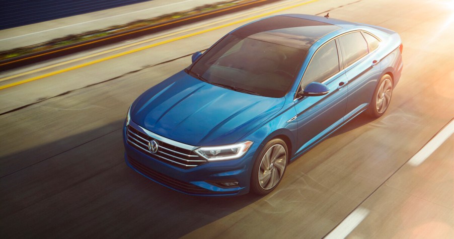 A blue 2023 Volkswagen Jetta driving down the street