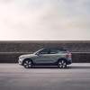 A silver 2023 Volvo C40 Recharge parked in front of a grey stone wall on blacktop.