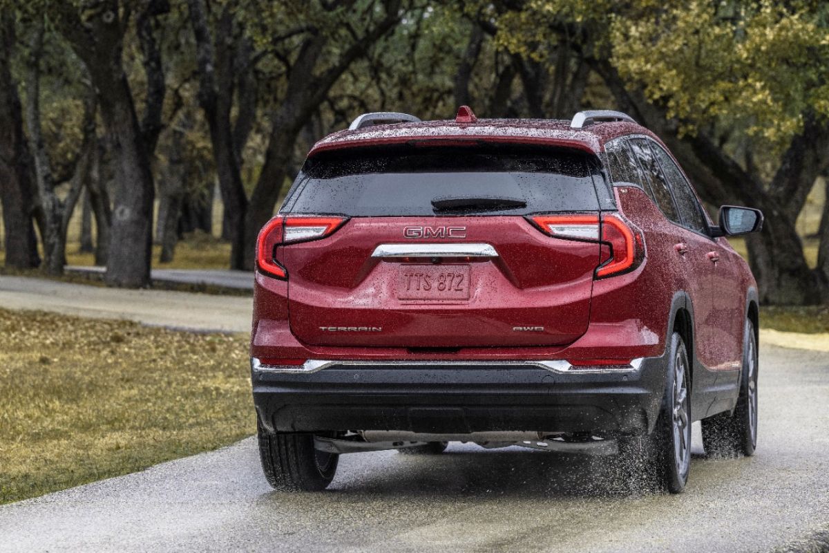 A red 2023 GMC Terrain driving on a wet road.