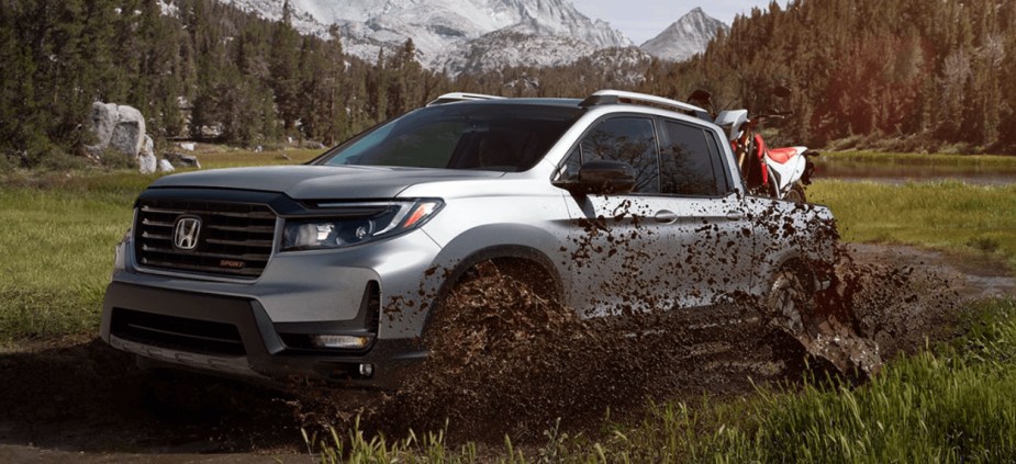 A Honda Ridgeline pickup truck drives with a dirt bike in its bed.