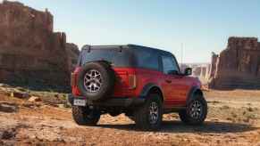 A red 2023 Ford Bronco faces toward desert rock formations. The Bronco is one of the most capable new off-road vehicles available today.