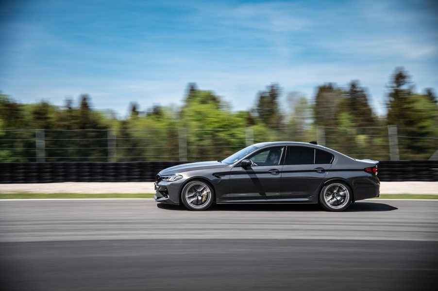 A dark gray BMW M5 blasts down a straight on a track.