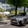 A gray BMW iX driving down a city street.