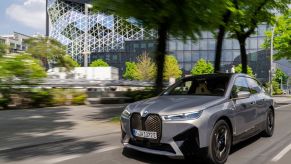 A gray BMW iX driving down a city street.