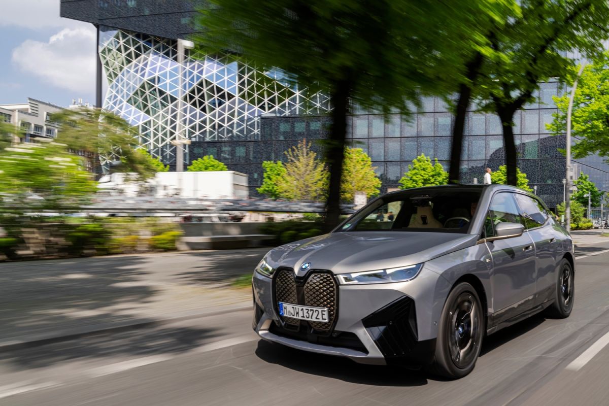 A gray BMW iX driving down a city street.