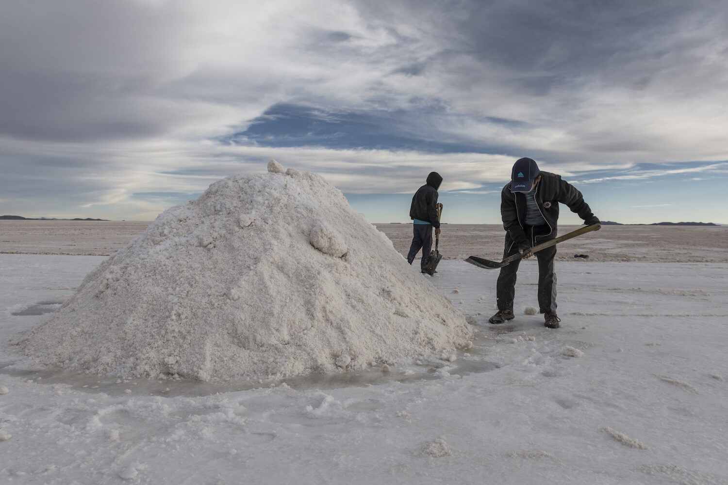 Bolivian lithium production workers shovel salt from the Salar de Uyuni flats to extract the minerals.