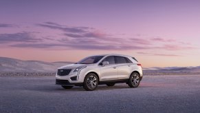 A white Cadillac XT5 sits on the salt flats at dusk.