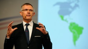 Stellantis CEO, Carlos Tavares stands in front of a world map during a keynote presentation.