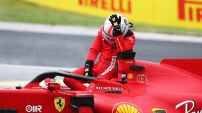 Scuderia Ferrari F1 Driver Charles Leclerc cradles his helmet in his hands.