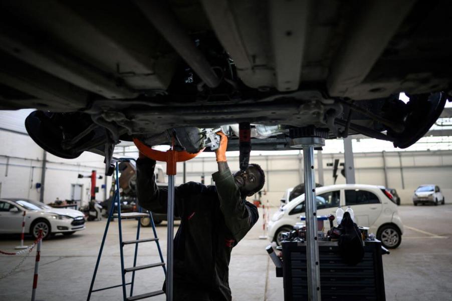 A mechanic technician performing maintenance on an electric vehicle at the Revolte e-garage in Carquefou, France