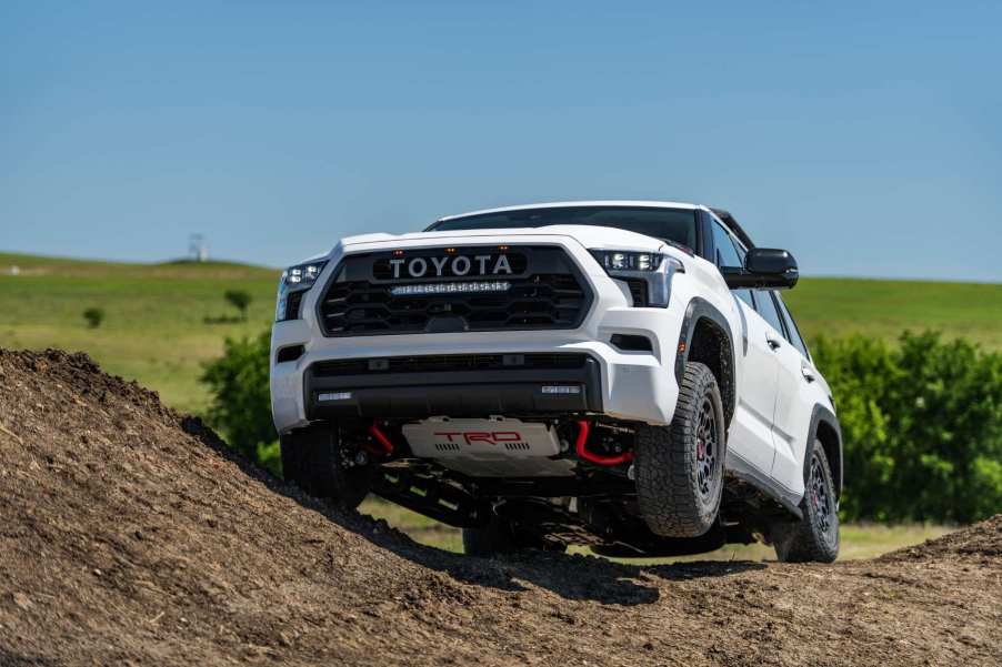 A white 2023 Toyota Sequoia TRD Pro demonstrates its capabilities on an off-road trail. The Sequoia is one of Toyota's reliable large SUVs