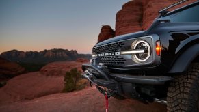 Front end of a black Ford Bronco on a red rock off-road trail.