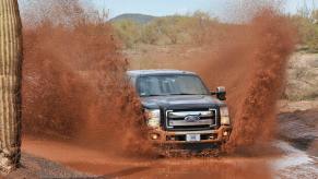 A Ford F-250 drives through some mud, it could need an oil change soon.