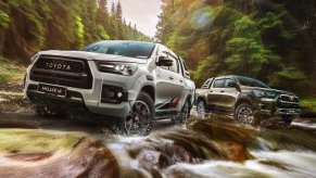 A pair of Toyota Hilux GR Sport midsize trucks driving off-road.