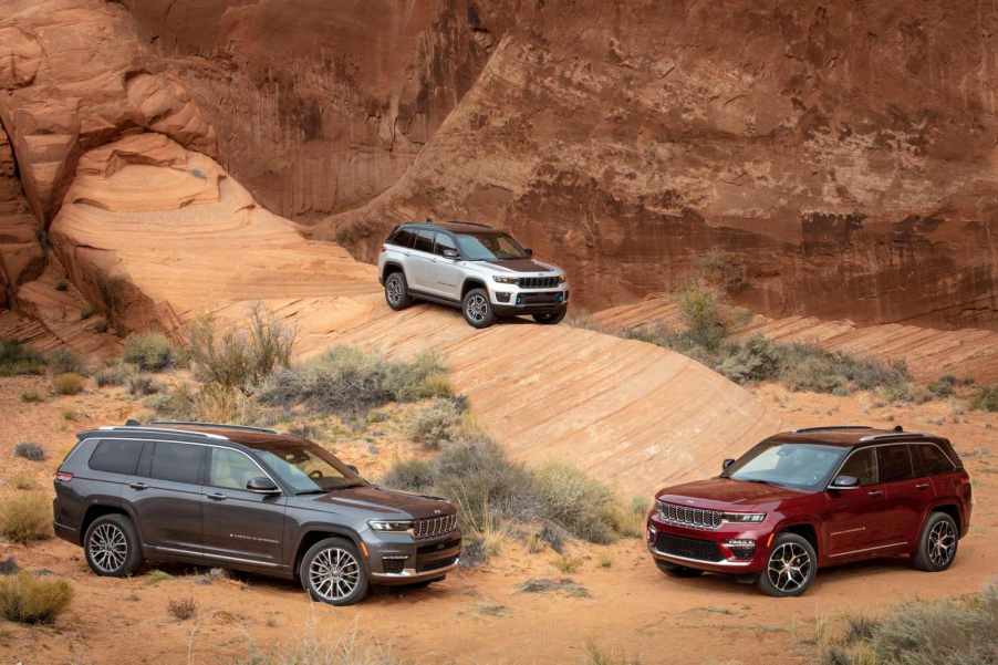 A Jeep Grand Cherokee, Grand Cherokee L, and Grand Cherokee 4xe posed amid desert sandstone formations.