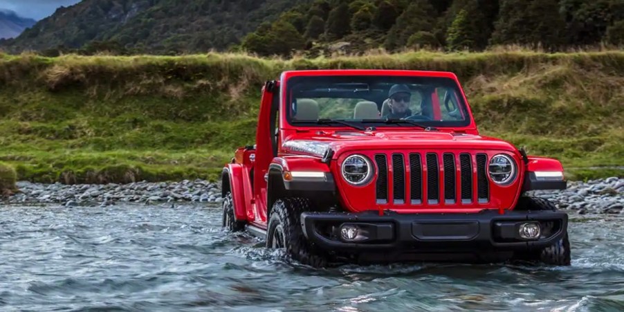 A Jeep Wrangler driving across a river.