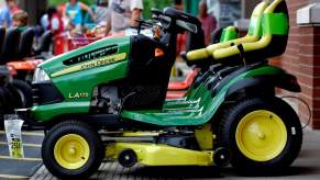 A green John Deere lawn mower parked outdoors that the owner may need to know how to charge a riding lawn mower battery during ownership.