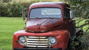 An old truck is parked at a junkyard.