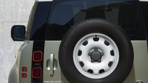 The rear-mounted spare steel wheel on a Land Rover Defender.