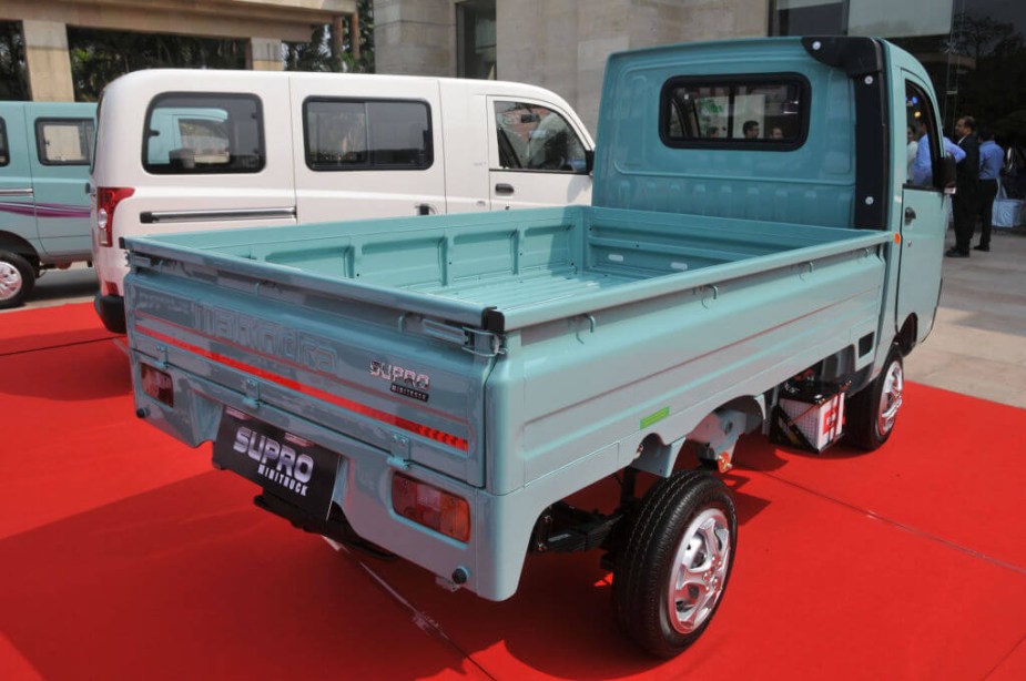 A Mahindra Supro mini-truck is parked with some other Kei cars.