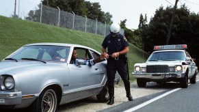 1970s POLICE OFFICER pulling a guy over in an old car