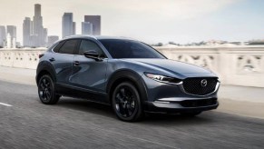 A blue 2023 Mazda CX-30 subcompact SUV is driving on the road.