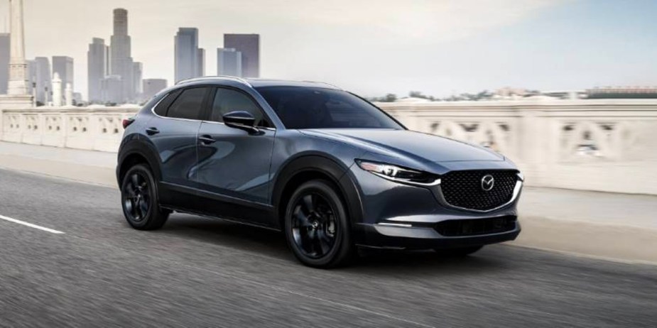 A blue 2023 Mazda CX-30 subcompact SUV is driving on the road. 