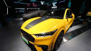 A yellow Mustang Mach-E with a large stripe down the center of the hood.