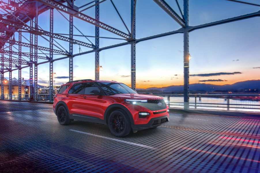 A red Ford Explorer crosses a bridge at sunset.