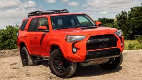 An orange Toyota 4Runner midsize SUV is parked off-road.