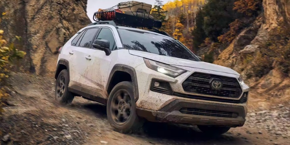 A white 2023 Toyota RAV4 small SUV is driving off-road. 