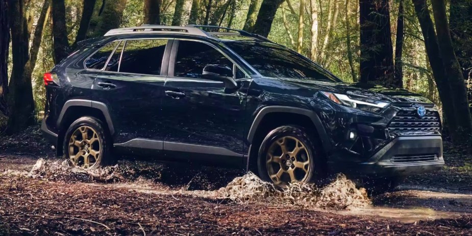 A blue 2023 Toyota RAV4 Hybrid small hybrid SUV is driving off-road. 