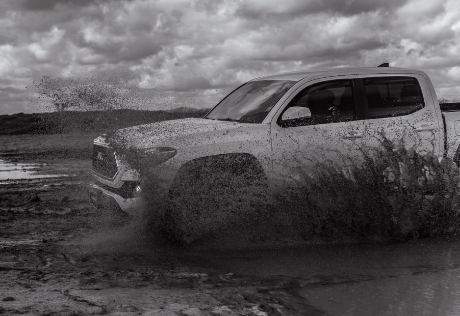 A Toyota Tacoma drives through a muddy field.