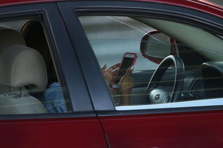 A woman distracted by her phone drives her car.