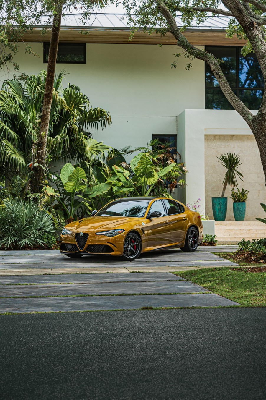 A mustard colored Alfa Romeo Giulia Quadrifoglio parked at a house