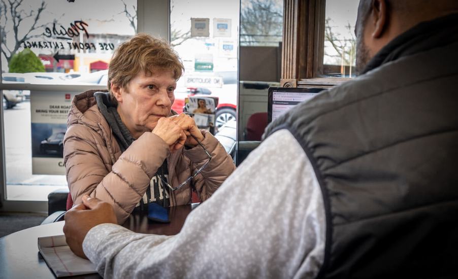 A customer sits in front of a salesperson at a dealership.