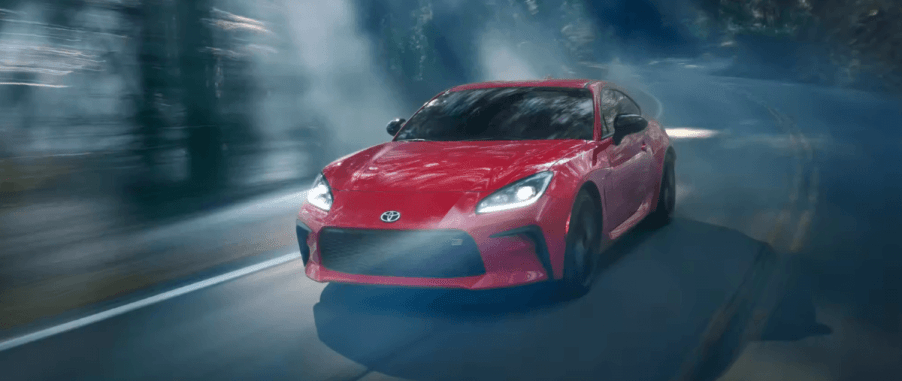 A red 2023 Toyota GR86 sports car fastback coupe model driving through a foggy forest at night