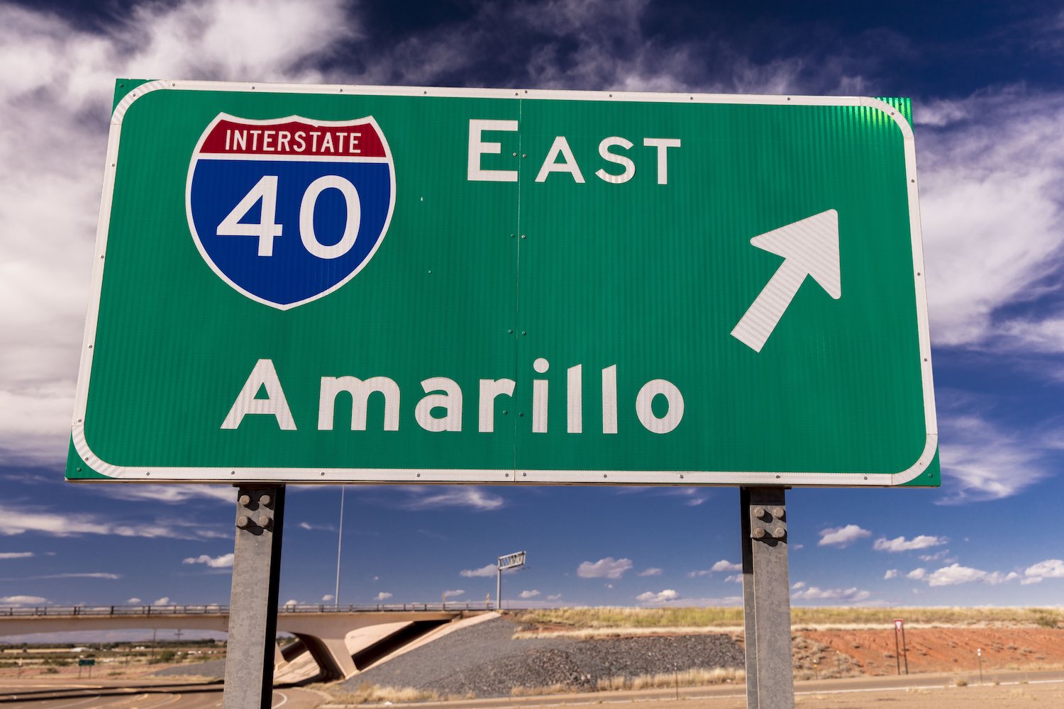 A sign for I-40 east towards Amarillo Texas via the interstate highway system, a blue sky visible in the background.