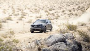 A blue 2023 Kia Telluride driving on a desert road.