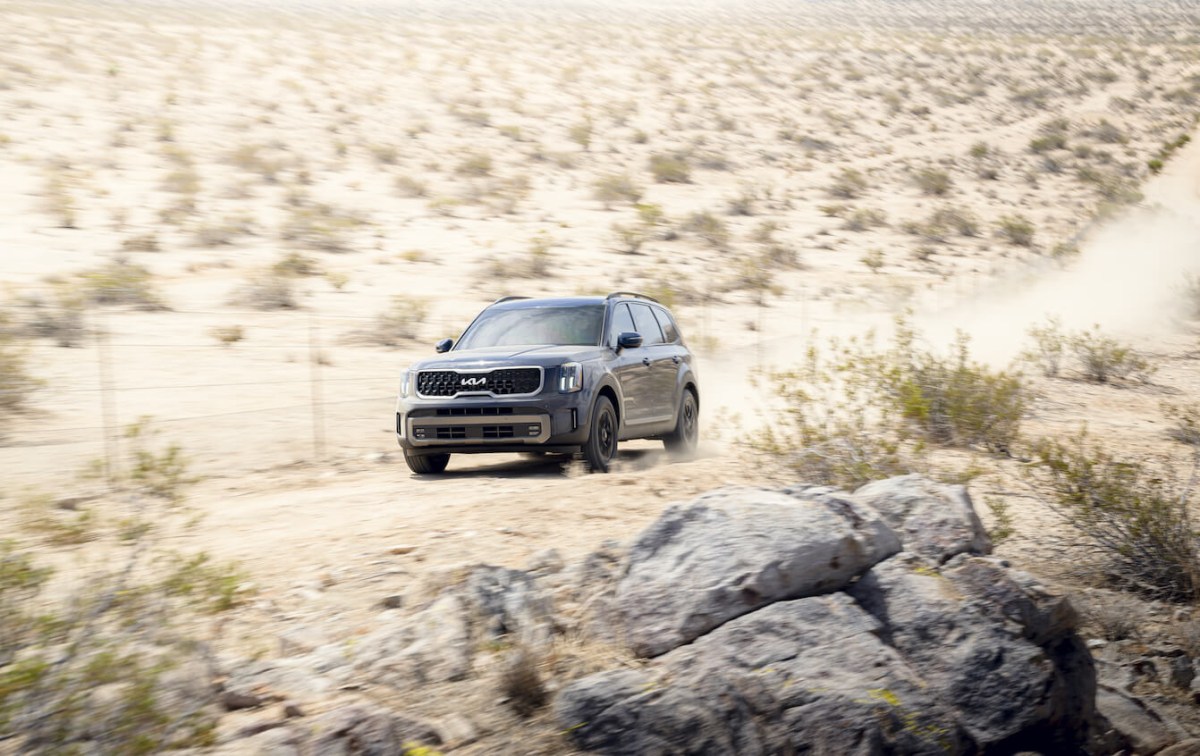 A blue 2023 Kia Telluride driving on a desert road.