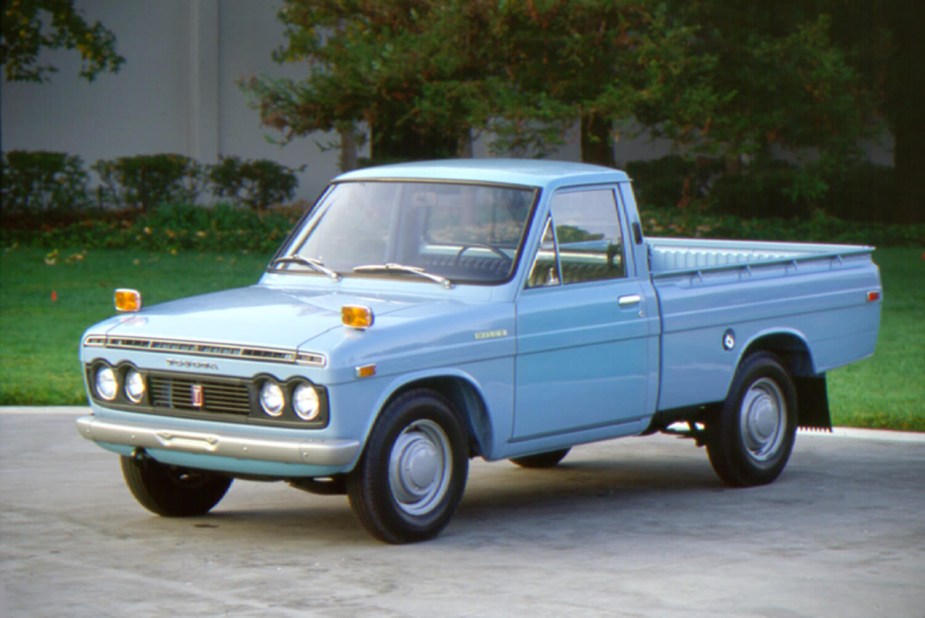 A light blue Toyota Tundra hi-lux pickup truck from 1971, parked in front of a lawn.