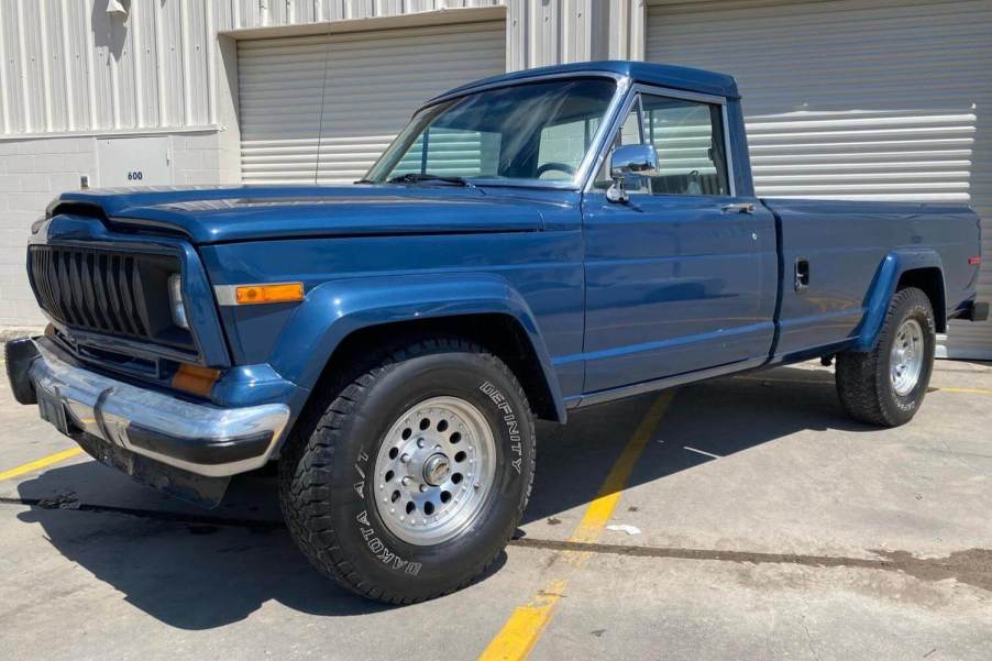 Old Jeep Gladiator pickup truck parked in front of a garage door.