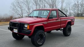 The front of a used Jeep Comanche classic truck fitted with a lift kit and rollbar.