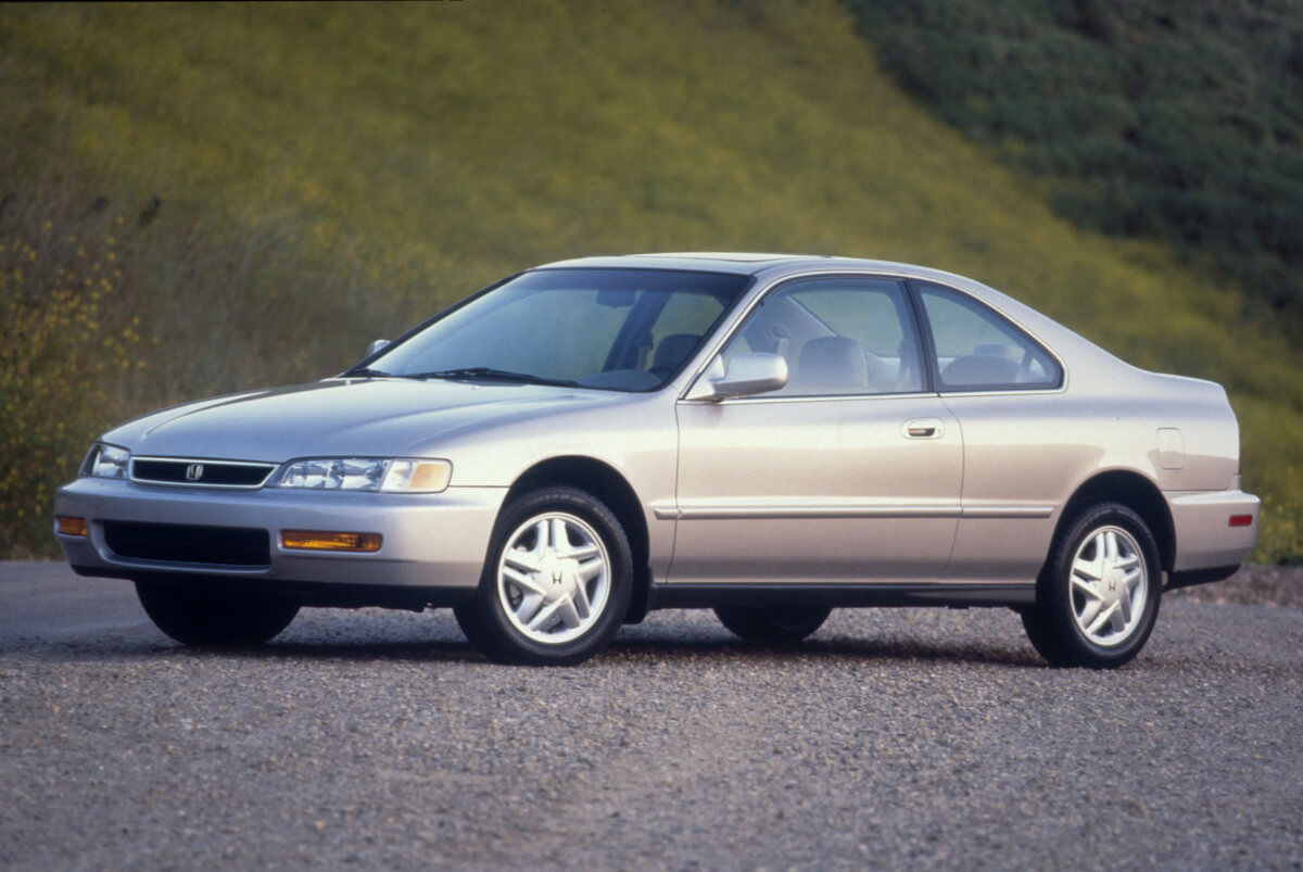 A 1997 Honda Accord, the understated car of Jeff Bezos, parks next to a grassy hill.