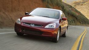 A used red 2004 Honda Accord cruises around a corner.