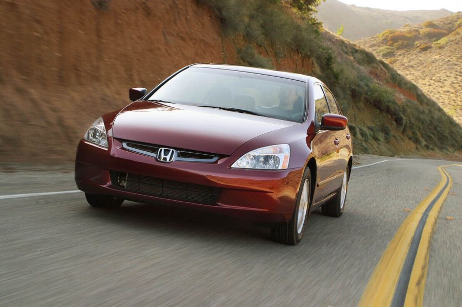 A used red 2004 Honda Accord cruises around a corner.