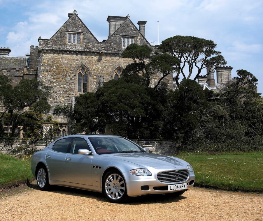 A silver 2004 Maserati Quattroporte parked in front of a castle