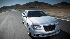 A silver 2014 Chrysler 300 SRT8 drives across an open road.